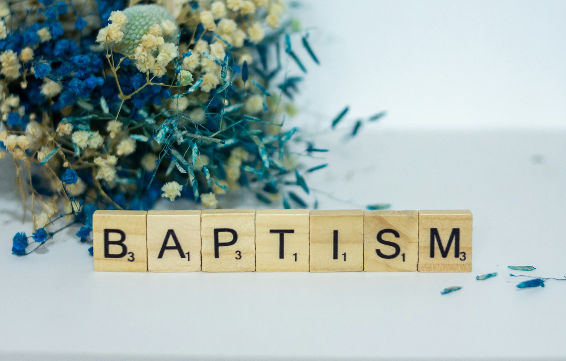 Baptism spelt out in scrabble tiles with flowers behind