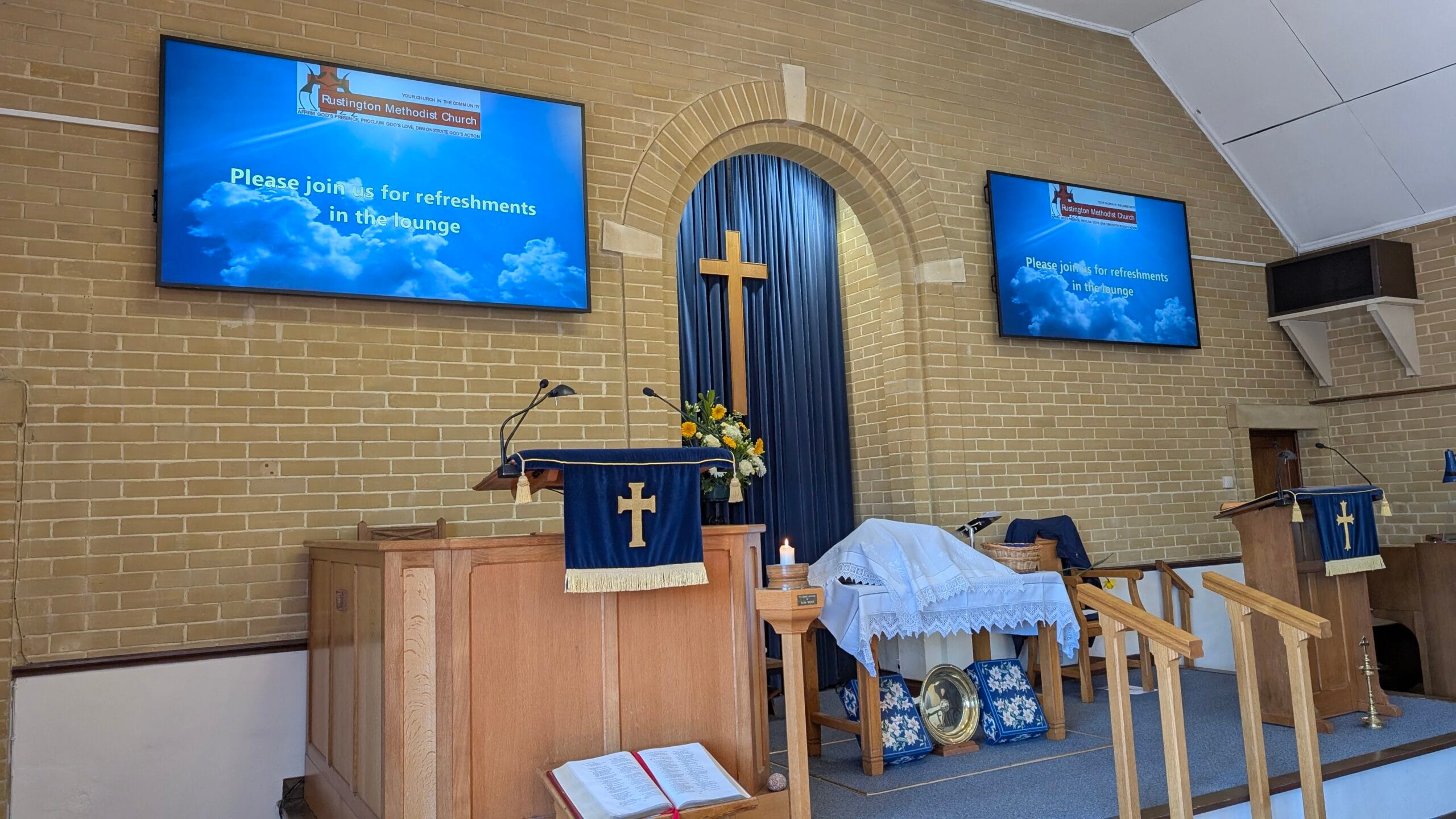A church interior featuring two large screens mounted on the wall, enhancing the worship experience for attendees.