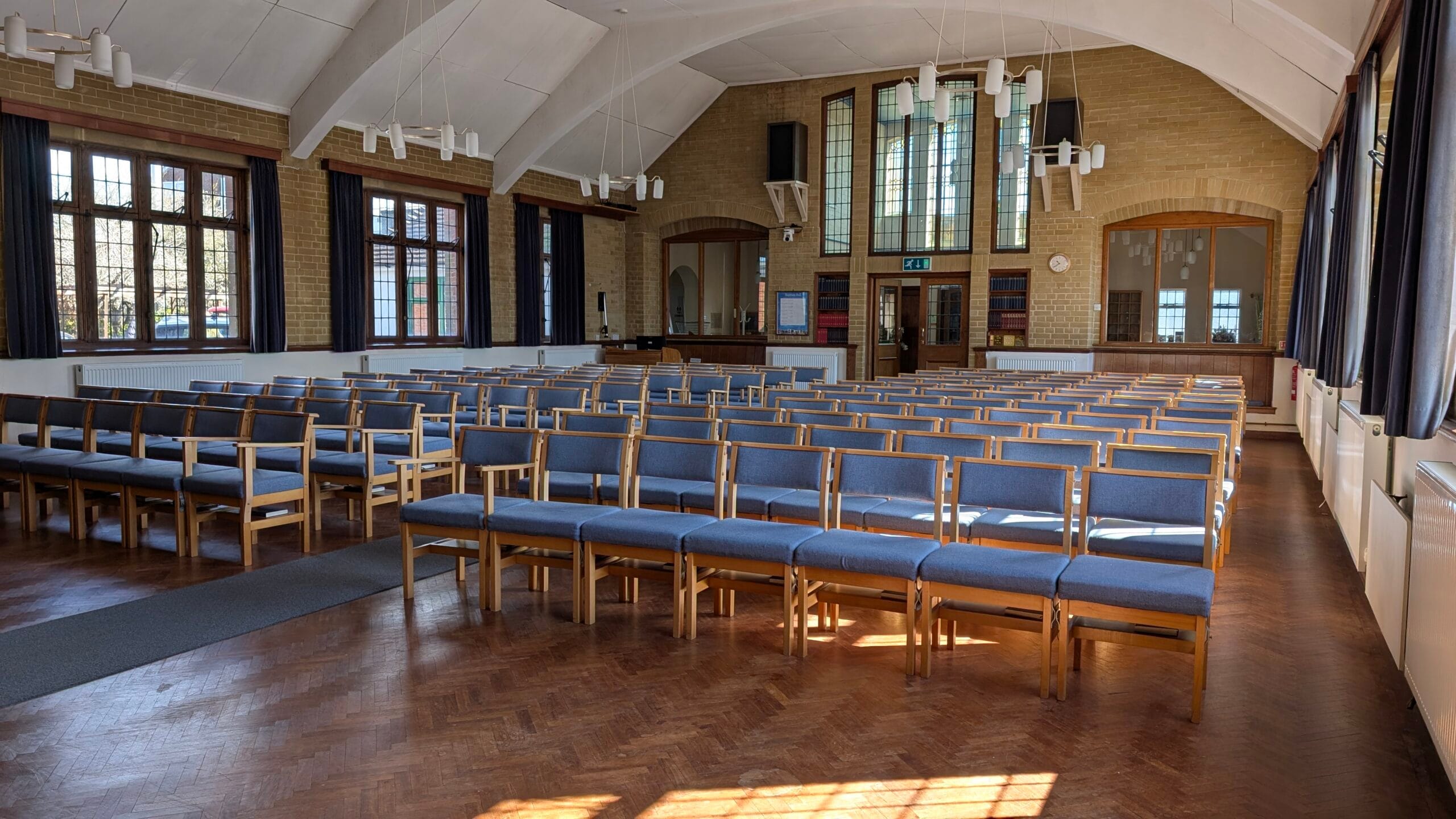 Rows of wooden chairs with pale blue cushions in a large church space