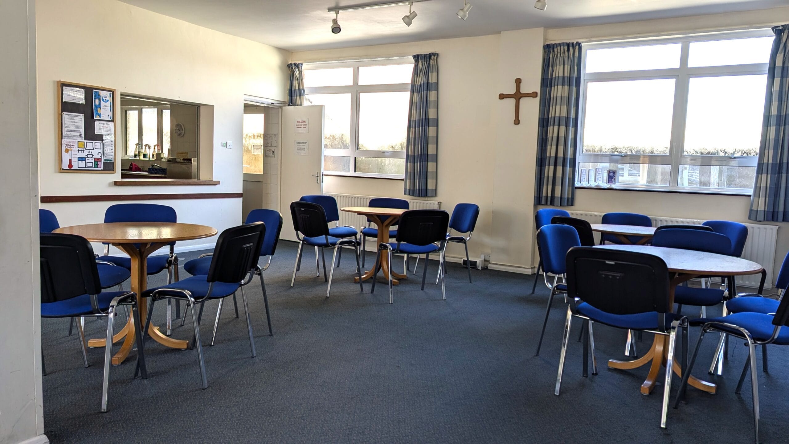 An interior view of a room filled with multiple tables and chairs, suitable for dining or group activities.